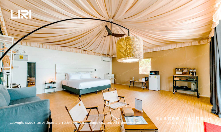 Luxury glamping tent interior bedroom ocean view — single-peak Indian tipi suite with draped fabric ceiling, king bed, resort accommodation