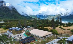 Aerial view of equestrian arena tent near lake and mountains