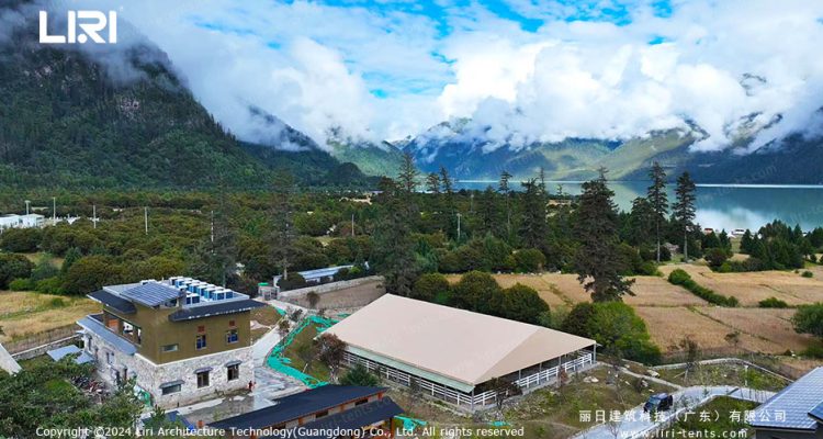Aerial view of equestrian arena tent near lake and mountains