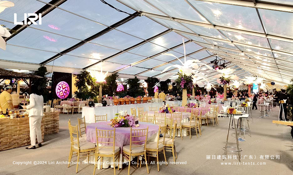 Banquet tables with pink tablecloths under transparent roof of clear-span tent