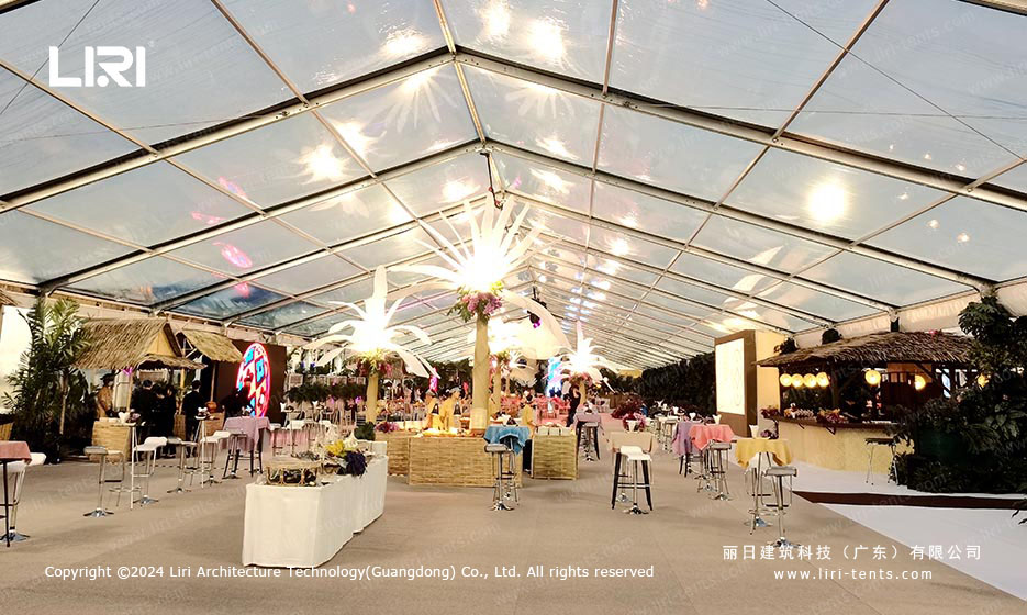 Wide interior view of clear-span tent with tropical bar setup and flower decorations
