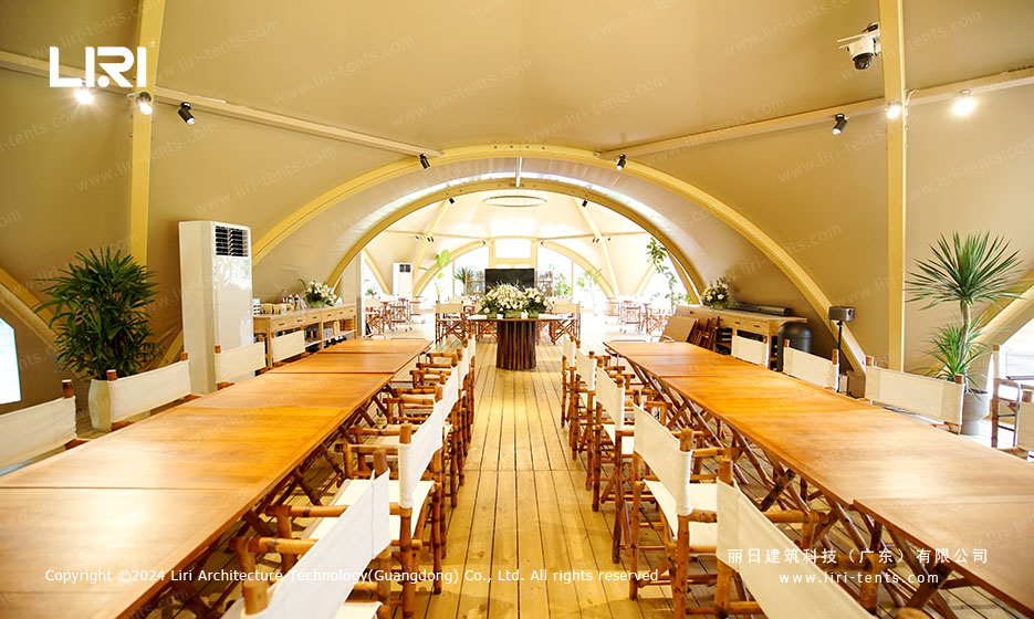 Long banquet table setup inside twin-peak tipi tent with chandelier lighting