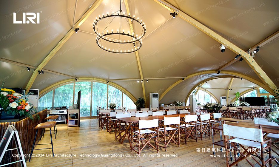 Interior of twin-peak tipi tent with dining tables and round chandelier for wedding