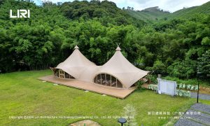 Twin-peak tipi tent with glass walls in mountain bamboo forest for wedding and glamping