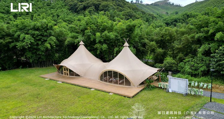 Twin-peak tipi tent with glass walls in mountain bamboo forest for wedding and glamping